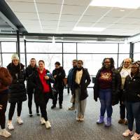 speaker gives directions to group of students who form semicircle in room